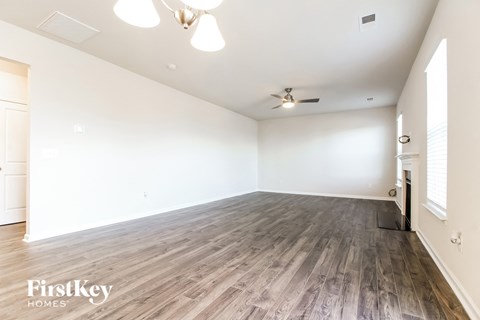 A spacious room with wooden flooring and a ceiling fan.