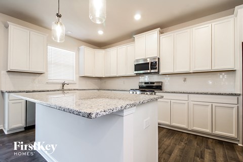 A kitchen with white cabinets and a granite countertop.