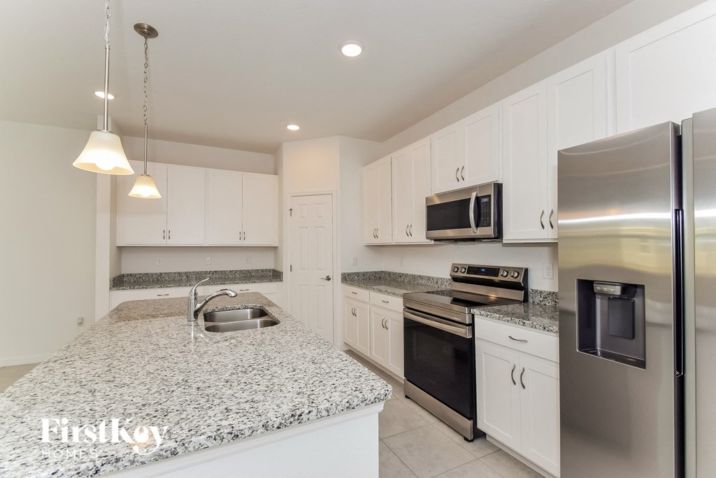 a white kitchen with granite counter tops and stainless steel appliances