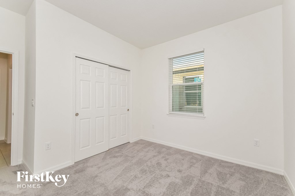 a bedroom with white walls and a white door and a window