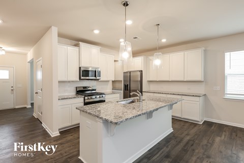 A modern kitchen with a granite countertop and white cabinets.