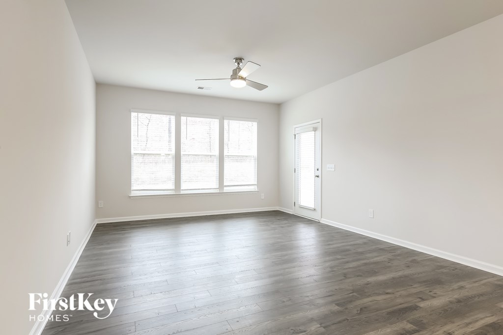 A spacious room with wooden flooring and a ceiling fan.