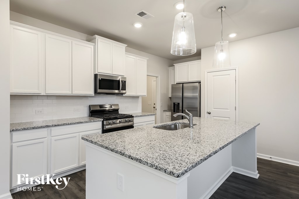 A kitchen with a granite countertop and white cabinets.