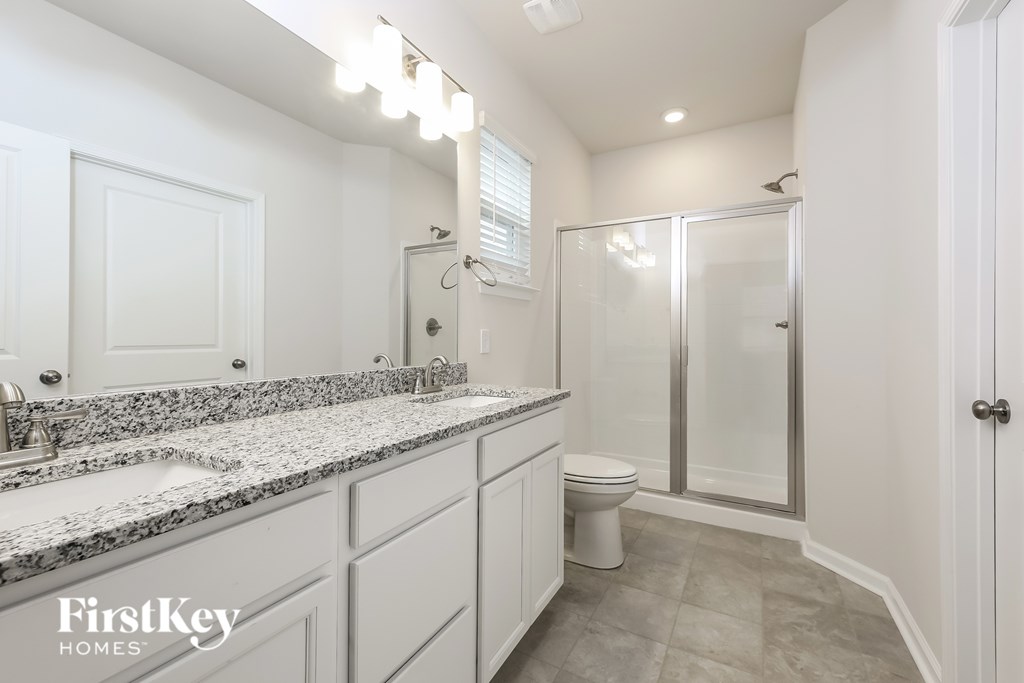A bathroom with a granite countertop and a walk-in shower.