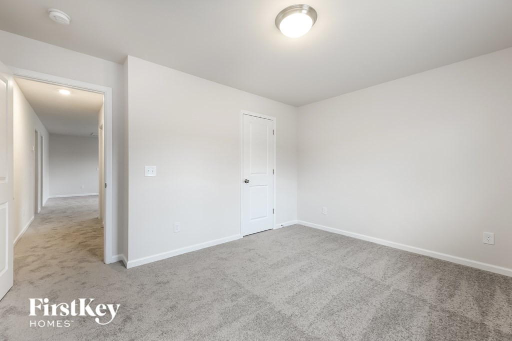A spacious room with a carpeted floor and a door on the right side.