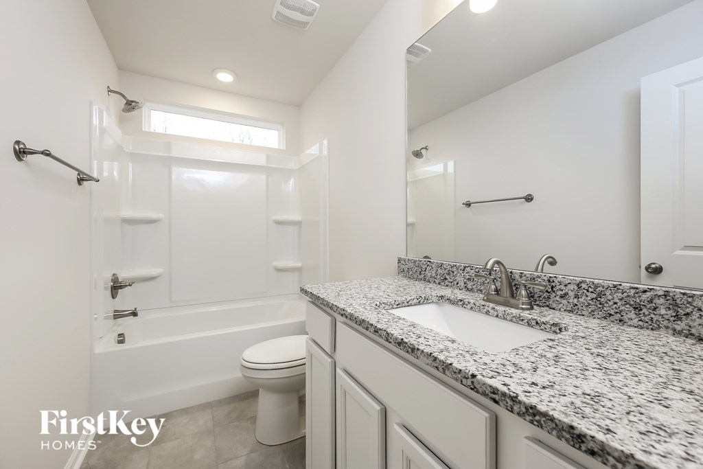 A bathroom with a granite countertop and a white toilet.