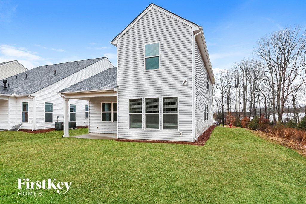 A white house with a grey roof and a green lawn in front.