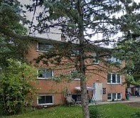 A red brick building with a tree in front.