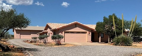 A house with a brown roof and a gravel driveway.