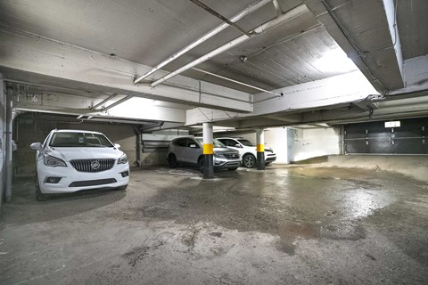 A white car is parked in a garage with other cars.
