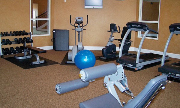 a gym with cardio equipment and weights on the floor