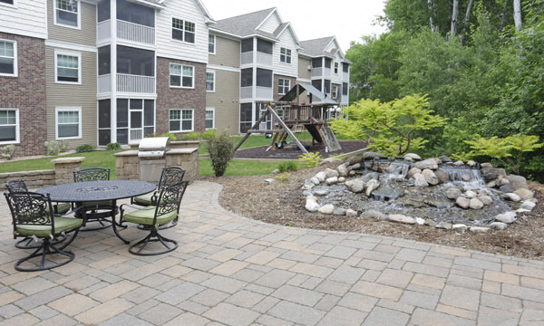 a patio with a fire pit in front of an apartment building