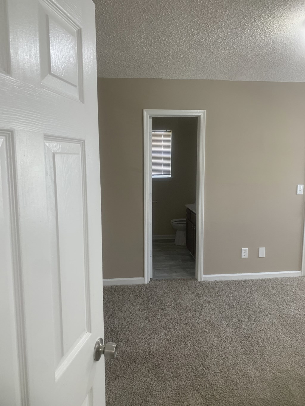 an empty room with a door open to a bathroom