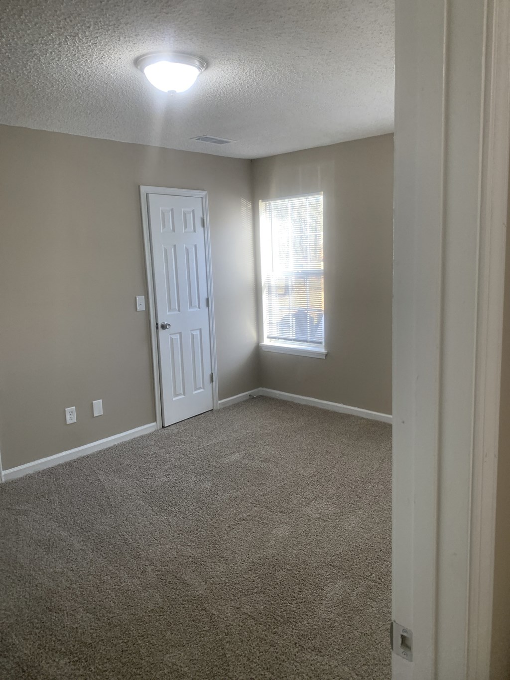 an empty living room with a white door and a window