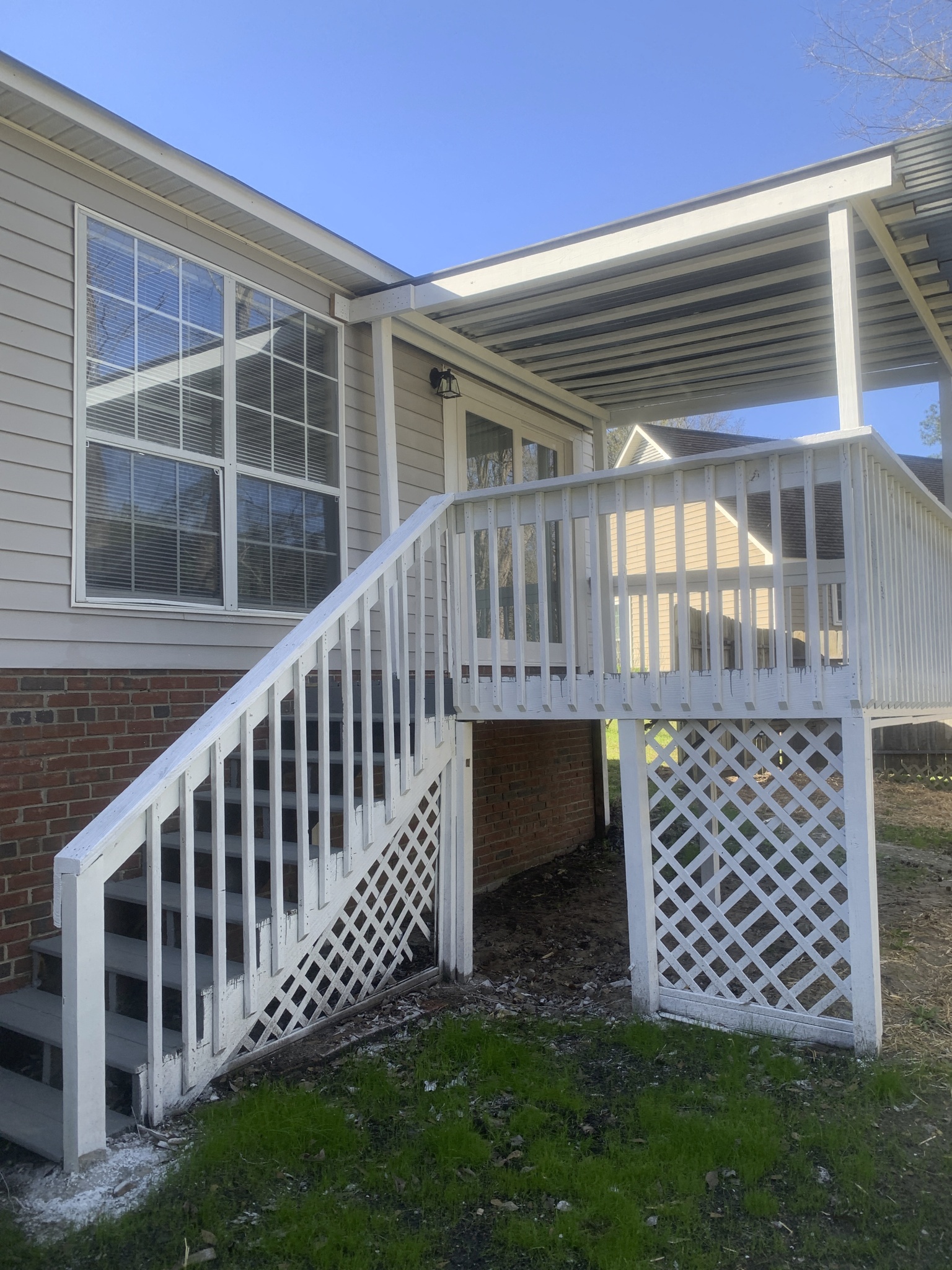 a porch with a white railing and stairs in front of a house