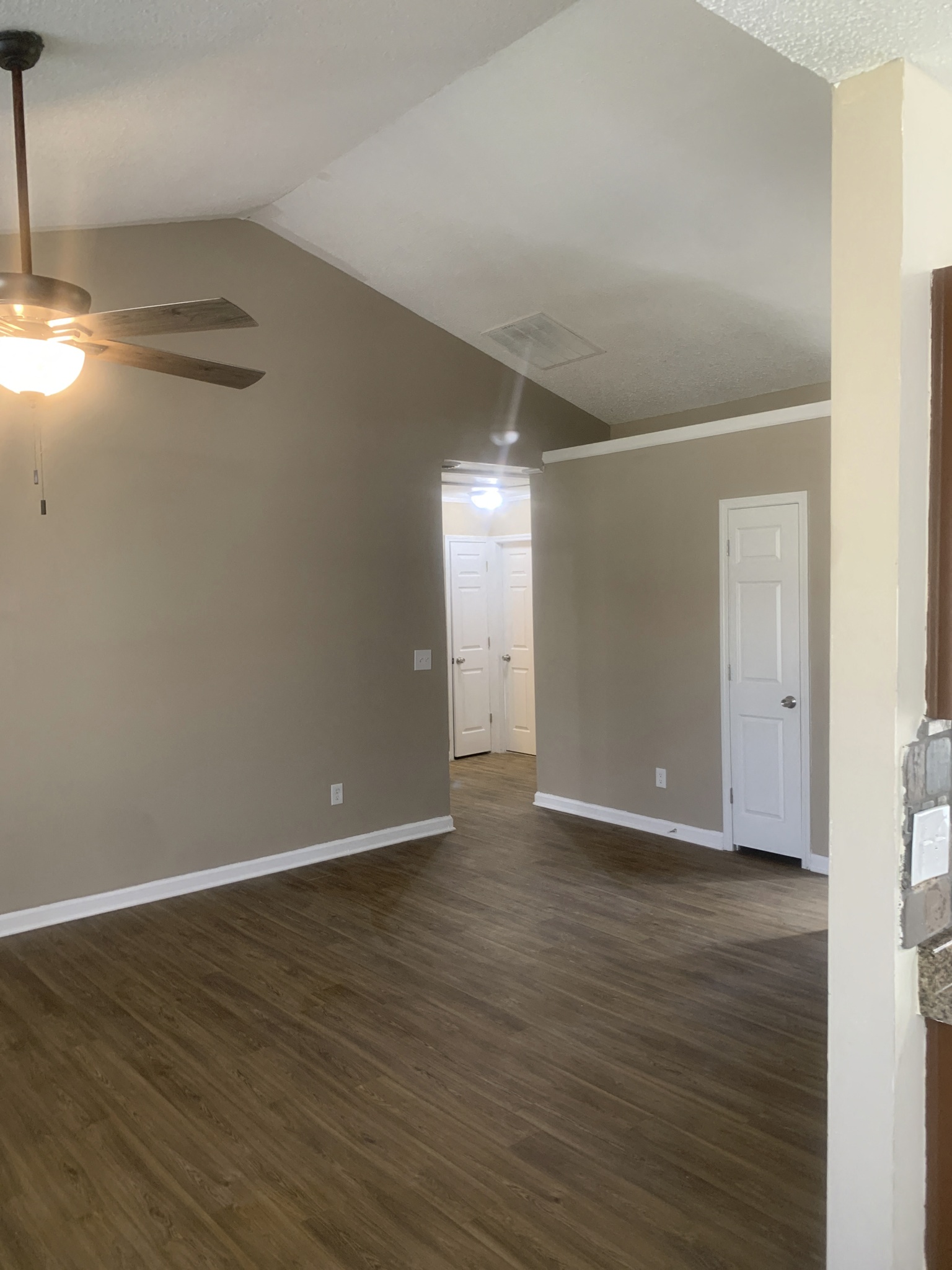 an empty living room with wood floors and a ceiling fan