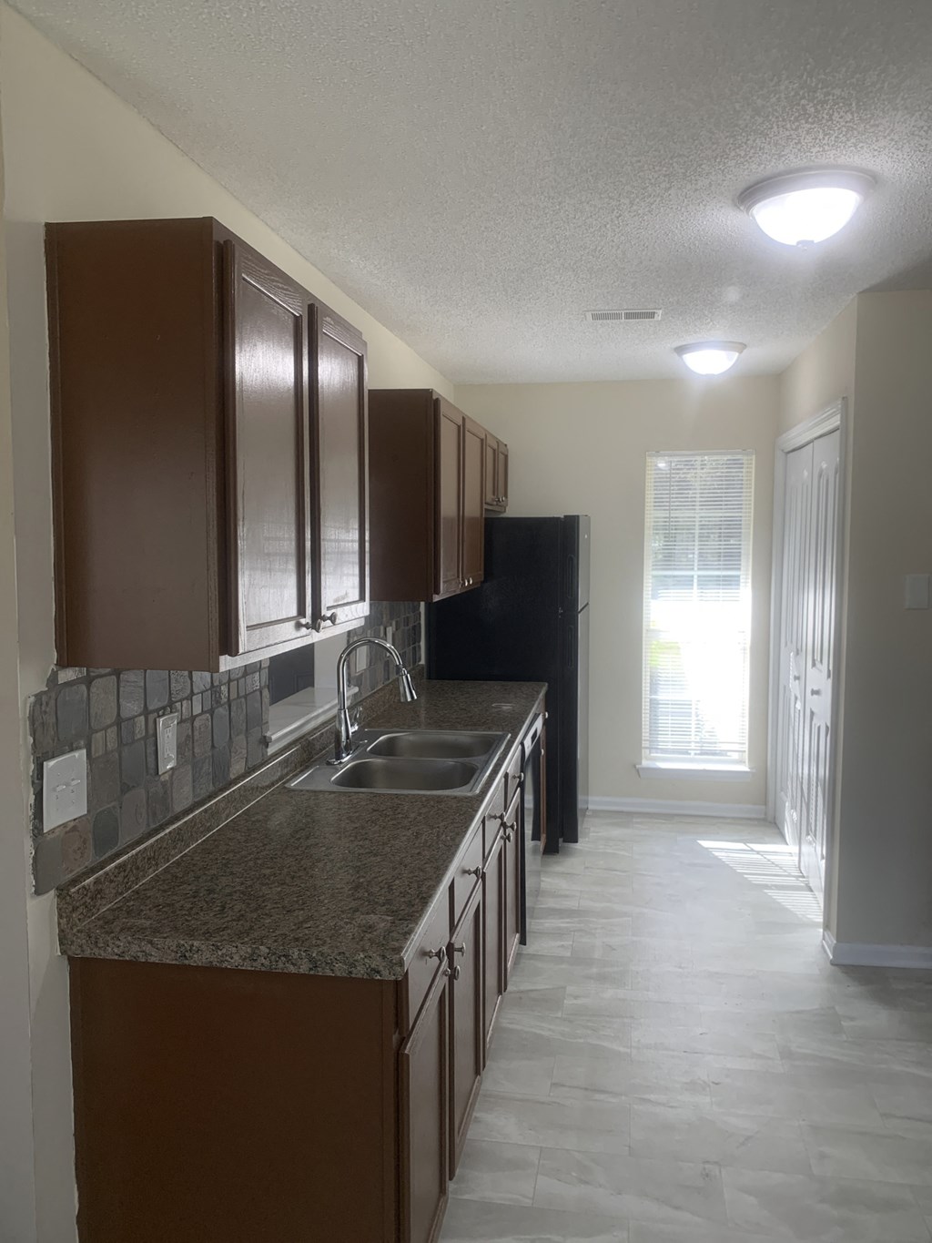 an empty kitchen with granite counter tops and dark cabinets
