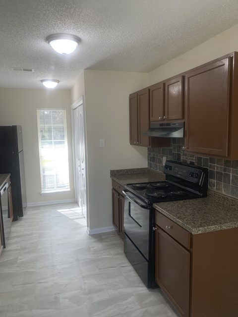 a kitchen with a stove and cabinets and a doorway