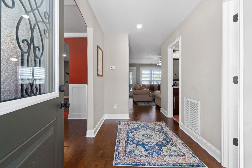 a long hallway with a rug and a door to a living room