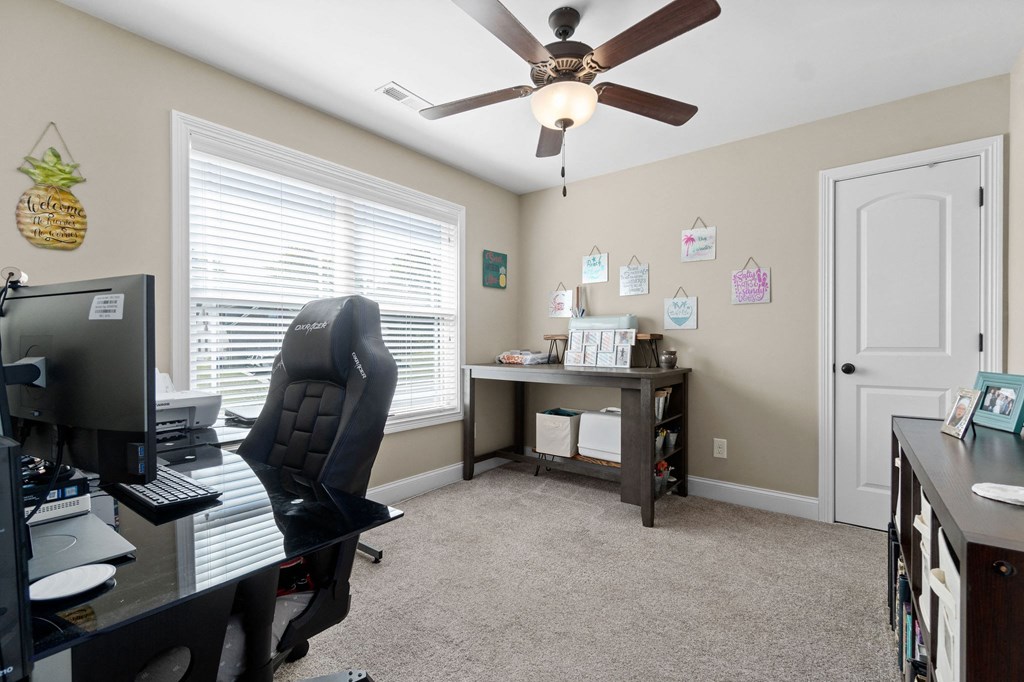 an office with a ceiling fan and a desk with a computer