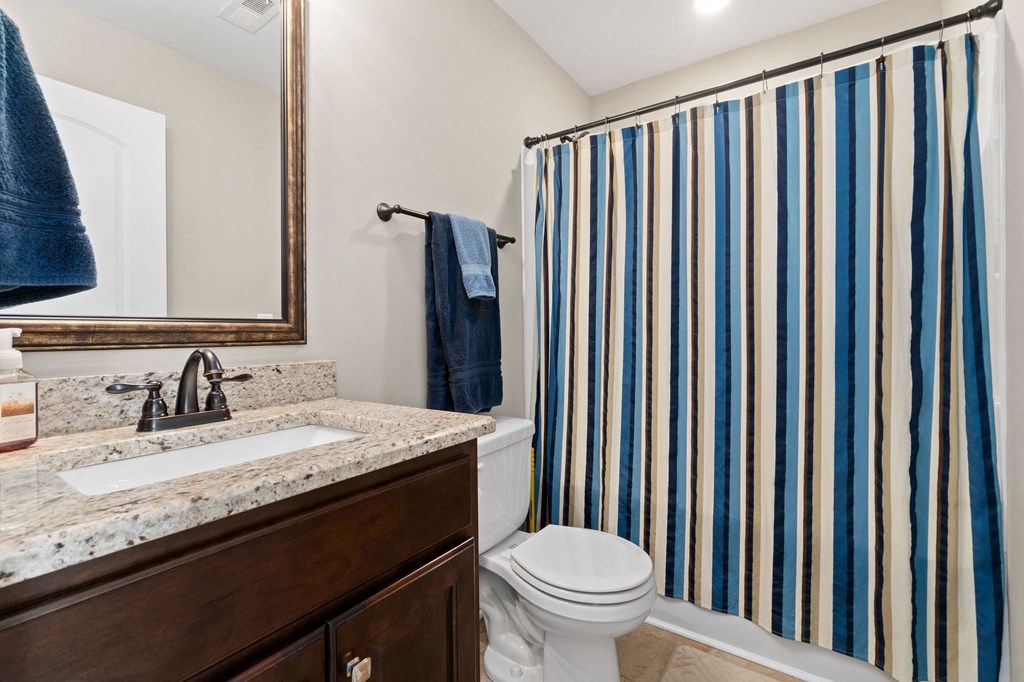 a bathroom with a striped shower curtain and a toilet and sink
