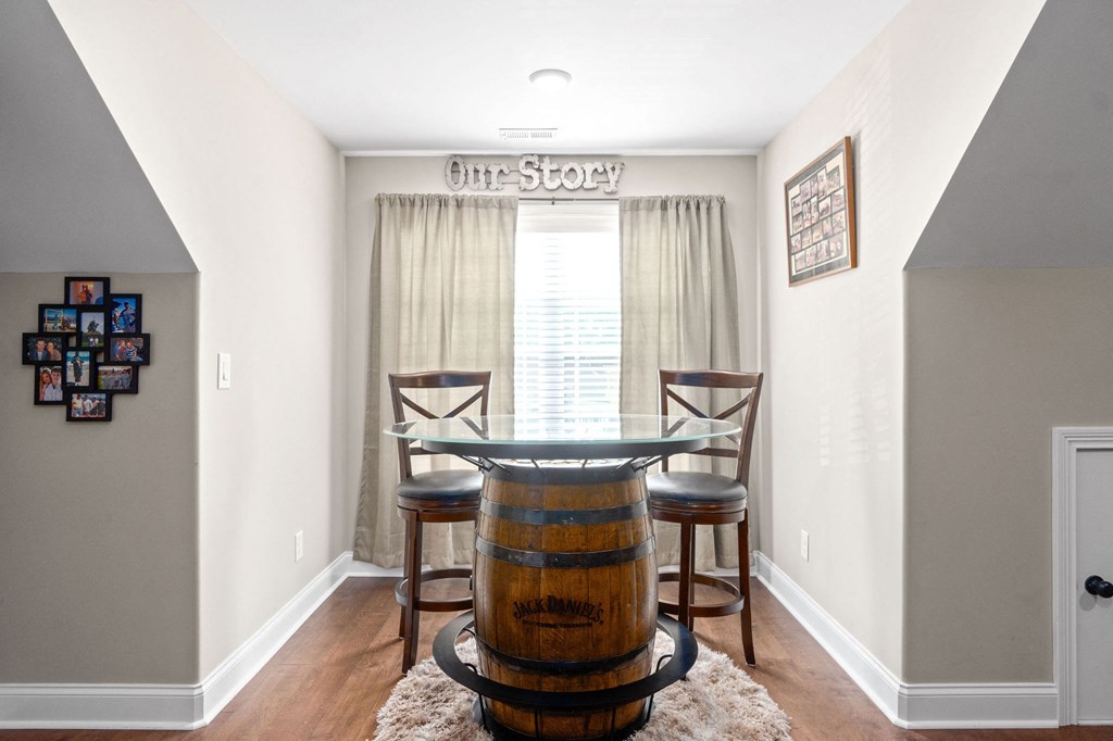 a dining room with a barrel table and chairs in front of a window