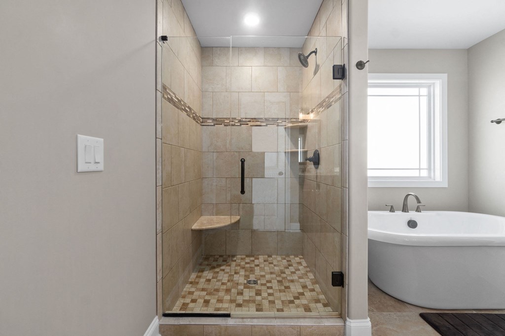 the master bathroom has a large tiled shower and a soaking tub