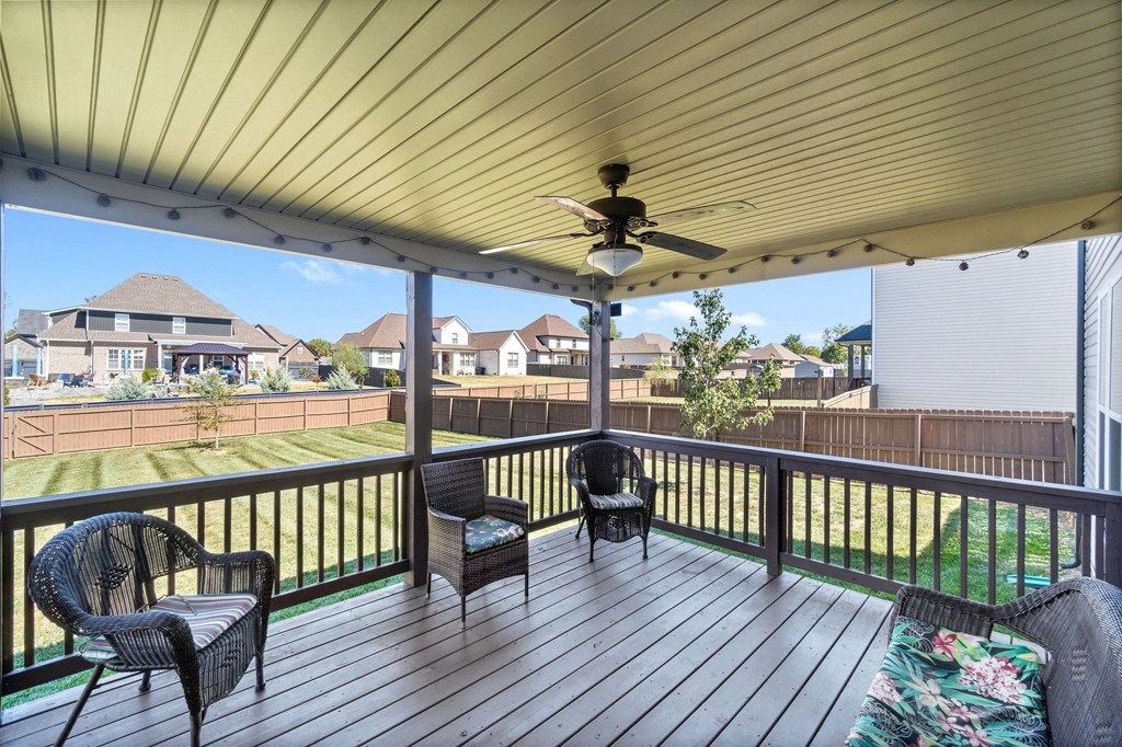 a covered deck with chairs and a ceiling fan