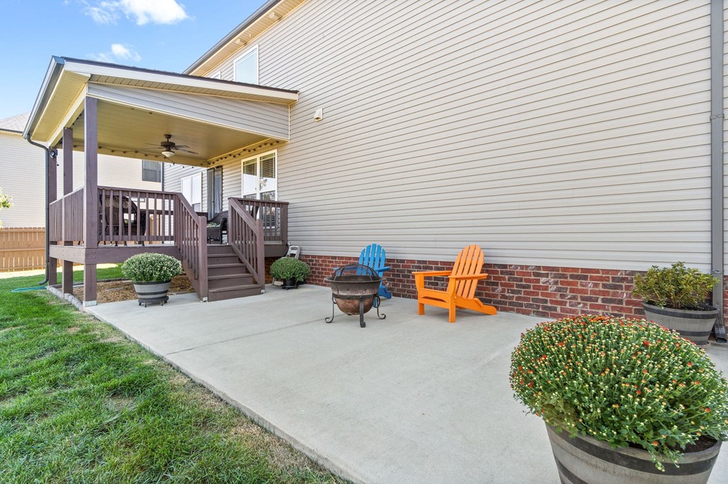 a patio with two chairs and a fire pit in front of a house