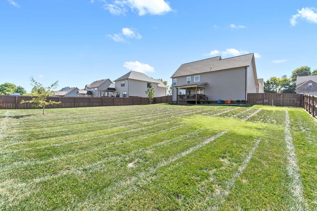 a yard with a fence and a house in the background