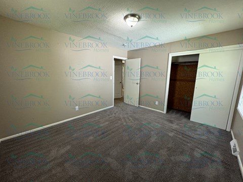 the living room of a new home with carpet and a door to the bedroom