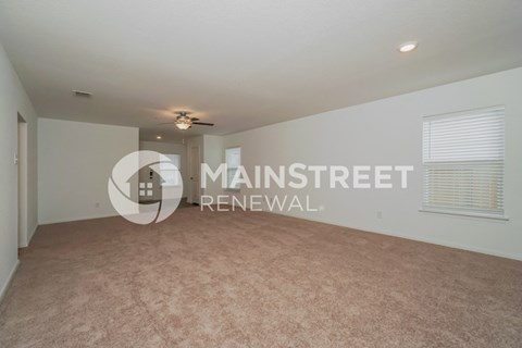 a spacious living room with carpet and a ceiling fan