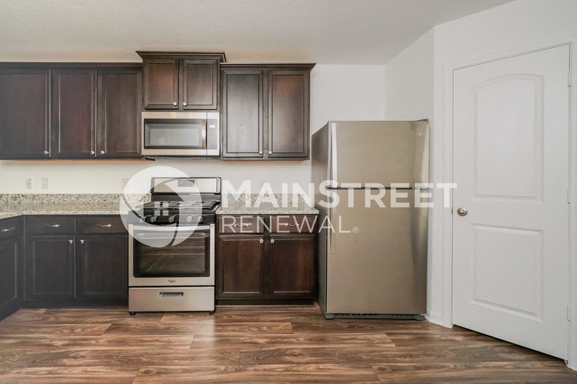 a renovated kitchen with dark cabinets and stainless steel appliances