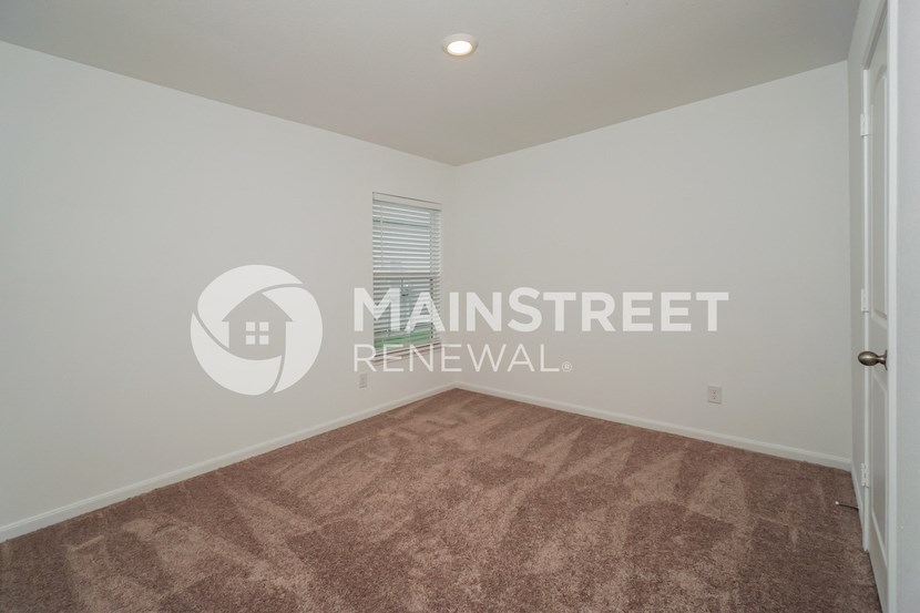 a living room with carpet and a door to a bedroom