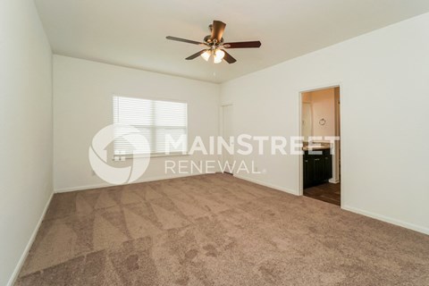 a living room with a carpet and a ceiling fan