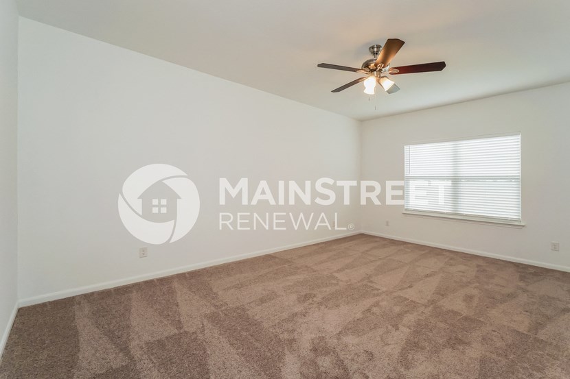 a living room with carpet and a ceiling fan