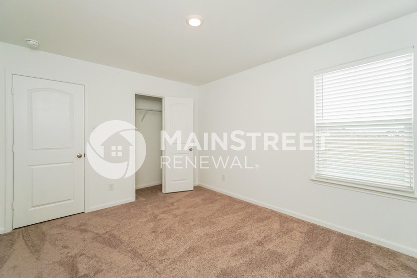 a bedroom with a closet and a door and a carpeted floor