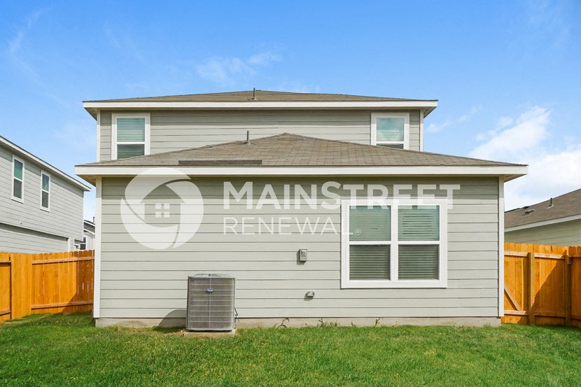 a small house with a yard and a wooden fence