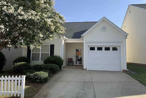 a white house with a driveway and a white fence