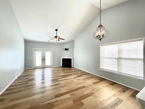 an empty living room with a large window and a ceiling fan