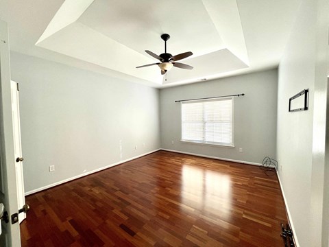 an empty room with wooden floors and a ceiling fan