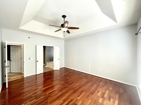 an empty living room with wood floors and a ceiling fan