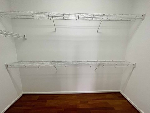 a walk in closet with shelves and a wood floor