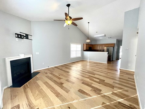 an empty living room with a fireplace and a ceiling fan