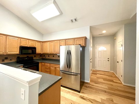 a kitchen with wooden cabinets and a stainless steel refrigerator