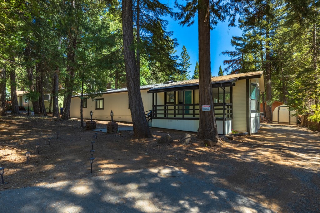 the front of a house in the woods with trees