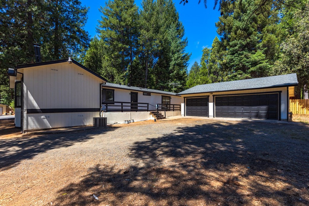 a house with two garages and a driveway and trees