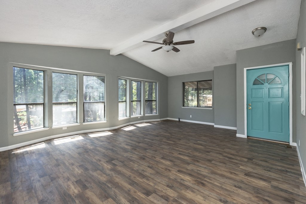 an empty living room with a ceiling fan and a blue door