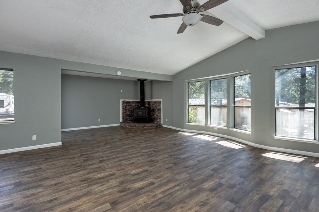 an empty living room with a fireplace and a ceiling fan