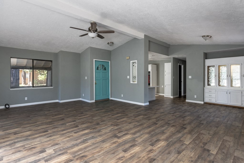 an empty living room with a ceiling fan and a blue door